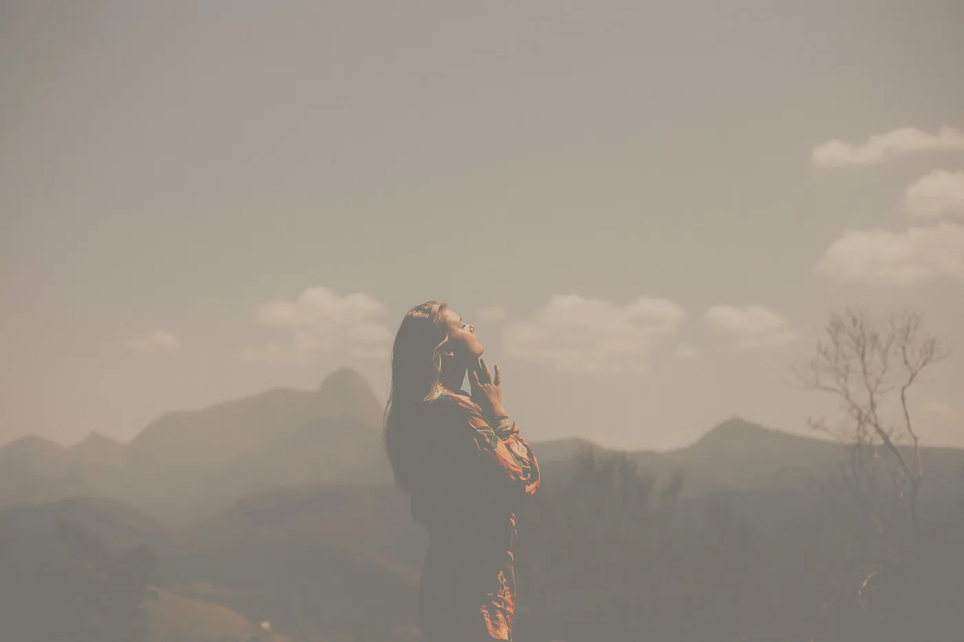 Femme respirant profondément face aux montagnes dans une brume dorée — retrouver son souffle et son équilibre avec la sophrologie